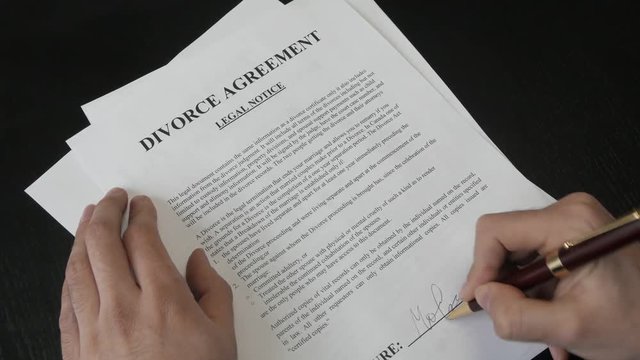 Signing a Divorce decree document. Closeup on the legal paper.