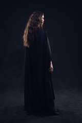 Beautiful naked gothic girl in a black cloak