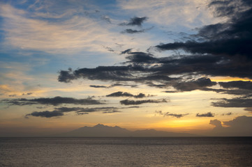 Sunrise Over Lombok Island, Indonesia. A dramatic sunrise over the Lombok Strait to the island of Lombok as seen from the Amed area of eastern Bali, Indonesia. Balinese fishing boats on the horizon.