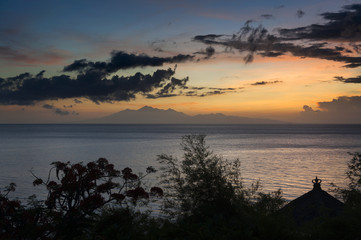 Sunrise Over Lombok Island, Indonesia. A dramatic sunrise over the Lombok Strait to the island of Lombok as seen from the Amed area of eastern Bali, Indonesia. Balinese fishing boats on the horizon.