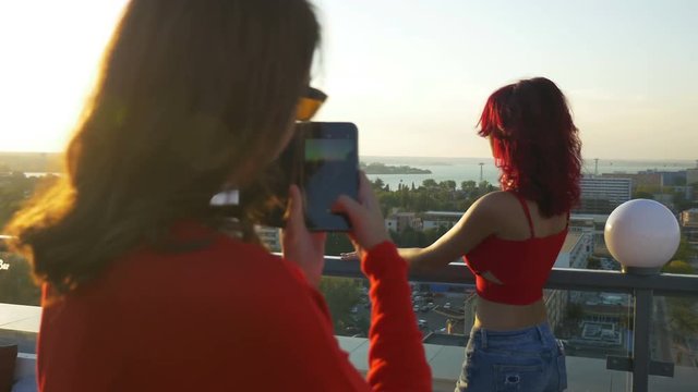 Two women having photo session with smartphone on a rooftop