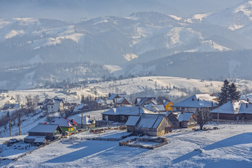 Picturesque rural landscape with traditional Romanian hamlet in the valley of Bucegi mountains on a cold winter afternoon, Pestera village, Bran-Rucar pass, Transylvania region, Romania.
