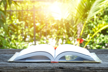Half open book on wooden table with nature background