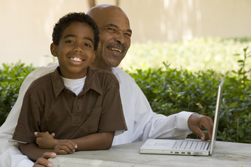 African American grandfather and grandson working on the computer.