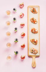  Catering, banquet food concept. Various snacks, brushetta sandwiches, gazpacho shots, desserts with berries on corporate event, christmas, birthday, wedding celebration over pink background, top view © sonyakamoz