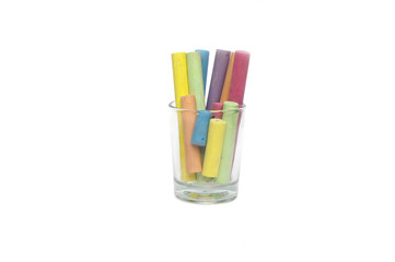 Close up multicolored chalk in glass cup on white background