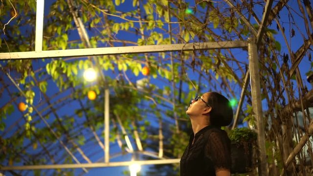 Asian woman looking at Spring Bitter Cucumber hanging in her business greenhouse farm