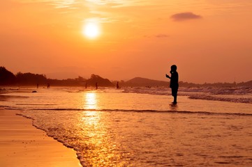 Fototapeta premium Silhouette boy standing on the beach at sunset