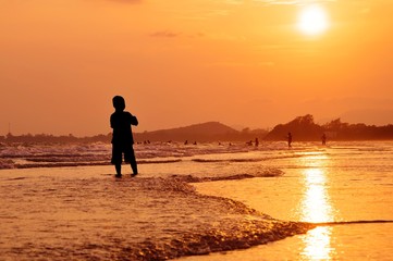 Fototapeta na wymiar Silhouette boy standing on the beach at sunset