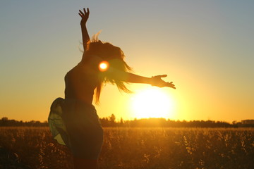 Attractive girl enjoy nature running, jumping, dancing in fields on sunset. Young woman in dress having fun outdoor. Summer holidays concept. 