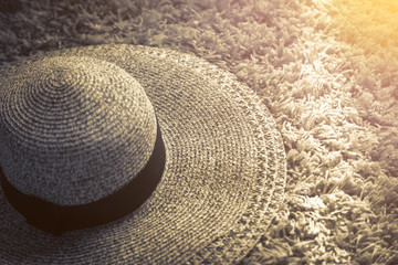 Fototapeta na wymiar Women's Wide Brim Straw Hat on rug with light from white window