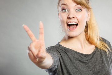 Cheerful lady makes v gesture.