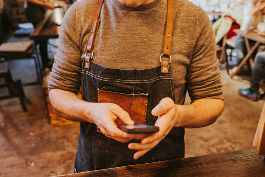 Man wearing unusual apron browsing phone