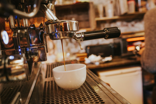 Fototapeta Espresso pouring in cup from coffee maker at cafe
