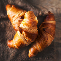 Golden fresh croissants  on old wooden background close up with