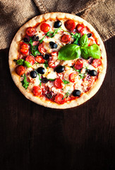 Hot pizza with Pepperoni Sausage on a dark background, top view.