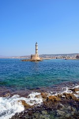 View of the Venetian lighthouse at the harbour entrance with rocks in the foreground, Chania, Crete.