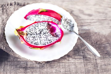 Dragon fruit on a white plate with spoon on wooden background cl