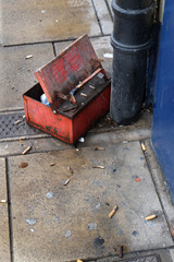 Steel cigarette waste box on pavement outside public house.