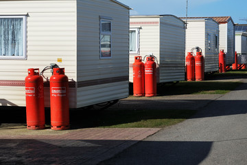 Red propane gas bottles outside large site mobile homes.