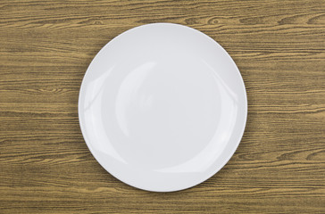 Top view of white plate on wood