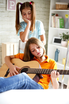 Teenagers learn to play guitar
