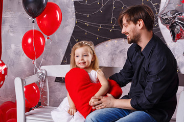 Father and daughter celebrating Valentine's Day. Father and little girl sitting on the bench, she...