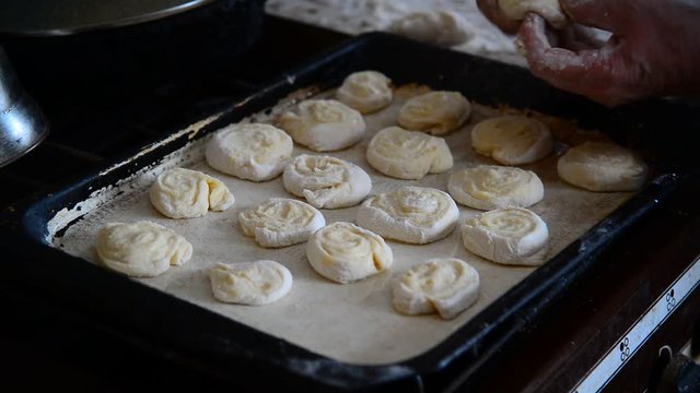 Grandma puts rolls of raw dough on baking tray