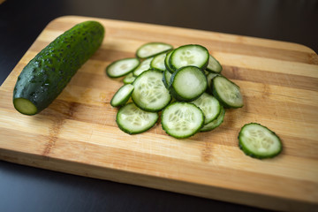 Sliced cucumber lying on a wooden board.