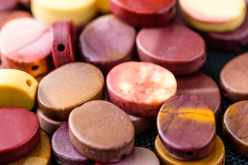 Colorful and polished mookaite jasper beads in oval shape on black weave.