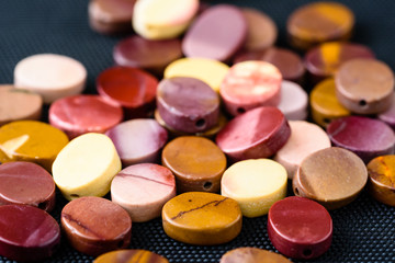 Colorful and polished mookaite jasper beads in oval shape on black weave.