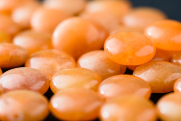 Collection of orange aventurine coin beads on black weave.