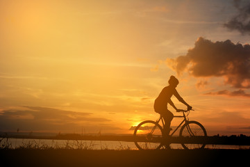 Silhouette of happy women with bicycle in nature at the sky sunset