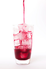 Summer drink: Pouring fresh grapes juice on ice in glass isolated on white background