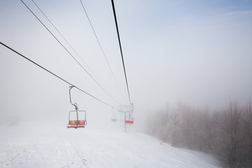 Fototapeta na wymiar Ski lift with seats going over the mountain 