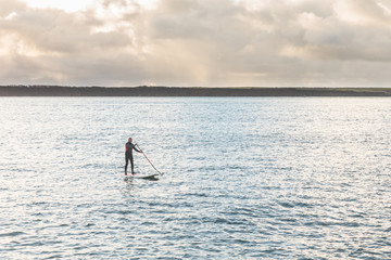 Plakat Man with paddle board over the cliffs