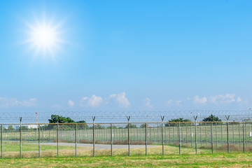 Fototapeta premium Closeup barbed wire fence for boundary on the grass with colorful sky.