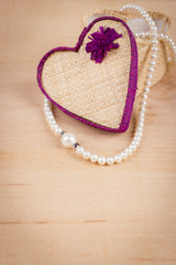 Elegant valentine background with white pearls and gift box shaped of heart on wooden background. Empty space for text
