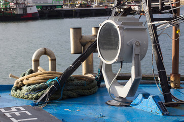 Large halogen beam swivel searchlight on the roof of the wheelhouse of a small trawler in harbor in County Down