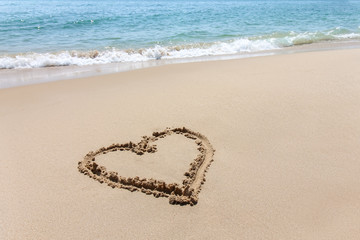 Heart shape, love symbol written at the sand beach