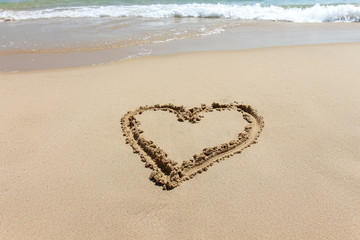 Heart shape, love symbol written at the sand beach