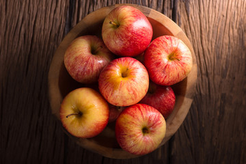 Naklejka na ściany i meble Red apples in a wooden bowl on dark background.