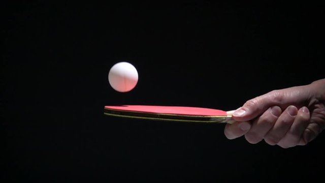 Hand holding table tennis racket and bouncing ping pong ball. Slow motion film clip with sport equipment.
