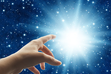 woman hand touching a divine light in the universe like a spiritual mystical concept