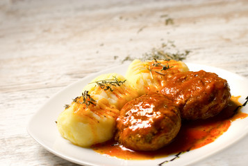 Delicious meal served on white plate - mashed potatoes and meatballs with tomato sauce
