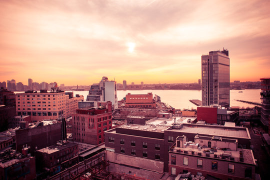 New York City sunset scene from the west side of Manhattan near the Meatpacking and Chelsea districts looking towards New Jersey with buildings and river in view.