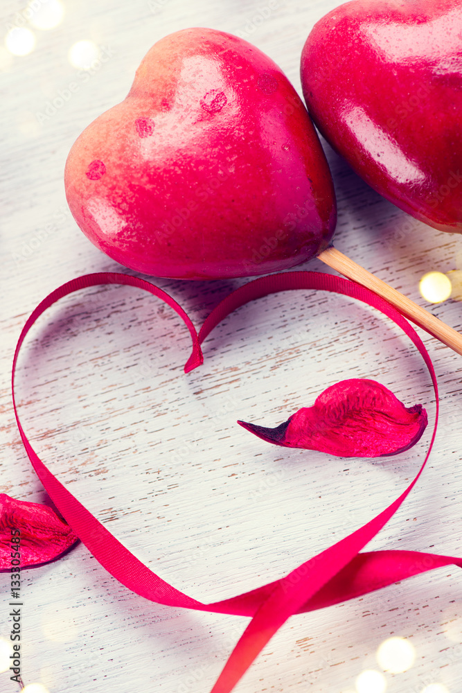 Sticker Valentine's Day. Elegant red satin gift ribbon and couple of red hearts over white wooden background