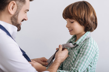 Close up of man tying tie for son