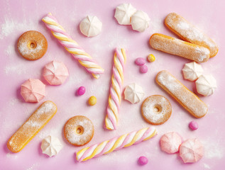 Fototapeta na wymiar Flat lay sweets and desserts on a pink background. Ladyfingers, meringues, cookies, marshmallows, biscuits, candies. Top view
