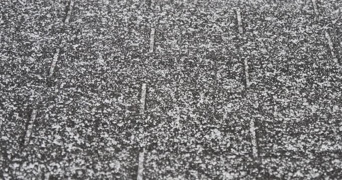 An extreme close-up shot of tiny, dangerous ice crystals falling on the house's roof during a winter ice storm. With audio.  	